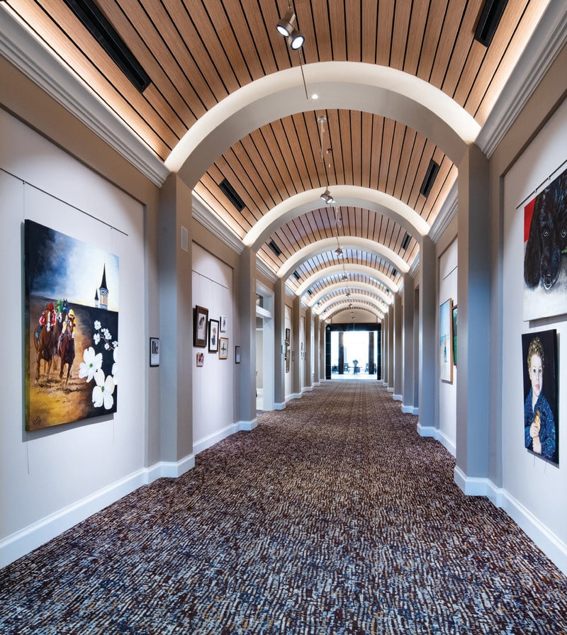 Long vaulted hallway with paintings hung on both walls. 